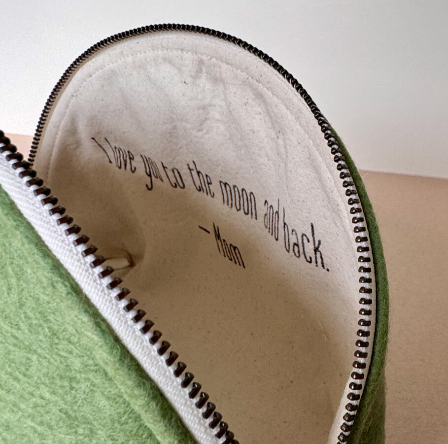Custom Message Pouch Close-up of a sage green wool felt pouch, opened to reveal a hand-stitched personal message inside: "I love you to the moon and back — Mom."